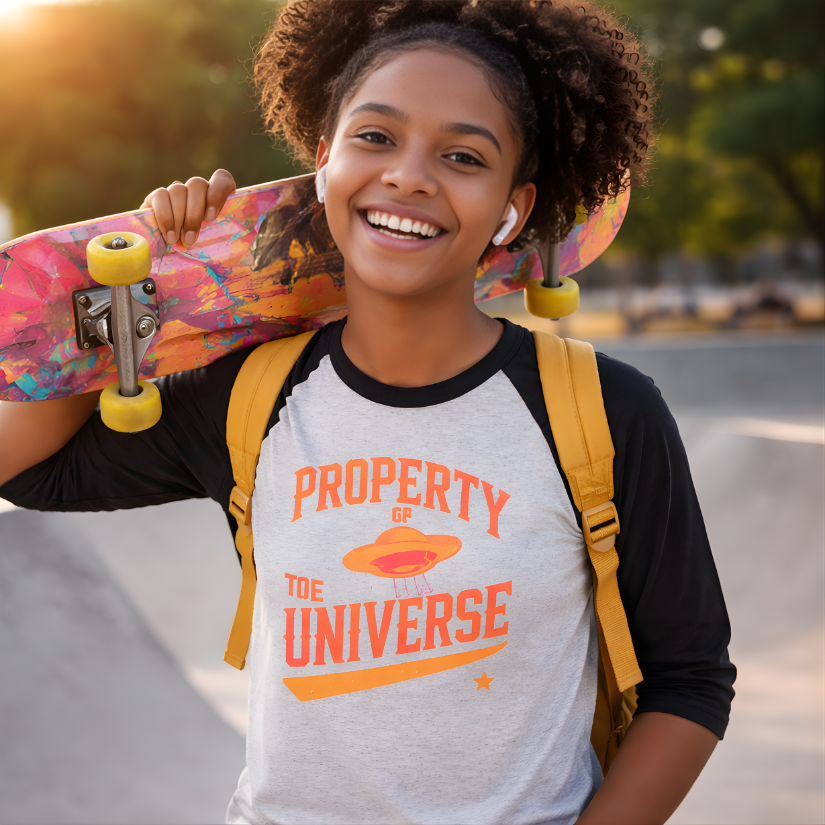 Person holding a colorful skateboard with a 'Property of the Universe' t-shirt and yellow backpack.