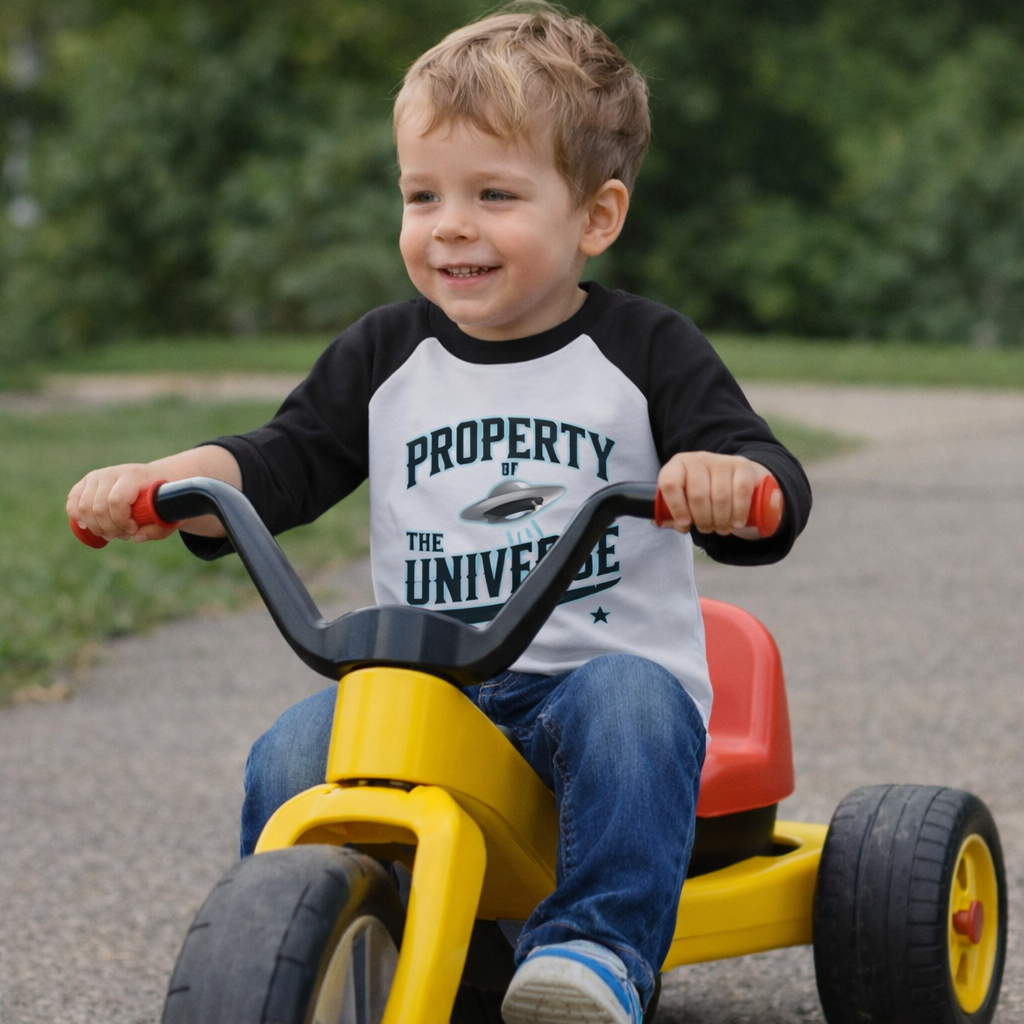 Child riding a toy bike outdoors with a blurred green background
